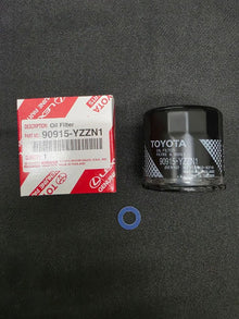 A Toyota engine oil filter with its red and white original packaging box and a blue gasket, displayed on a dark textured surface.